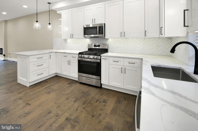 kitchen featuring a sink, a peninsula, white cabinets, stainless steel appliances, and open shelves