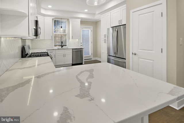 kitchen featuring a sink, stainless steel appliances, decorative backsplash, and white cabinetry