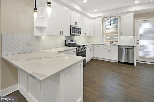 kitchen with a sink, a peninsula, white cabinetry, and stainless steel appliances