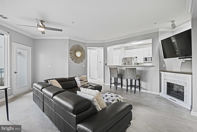 living room with baseboards, visible vents, a fireplace, ornamental molding, and ceiling fan