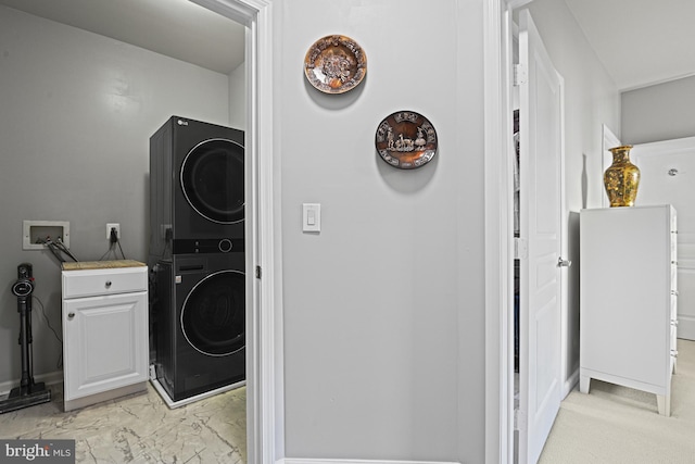 clothes washing area featuring cabinet space, marble finish floor, and stacked washer / dryer