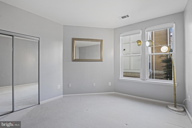 unfurnished bedroom featuring visible vents, baseboards, carpet, and a closet