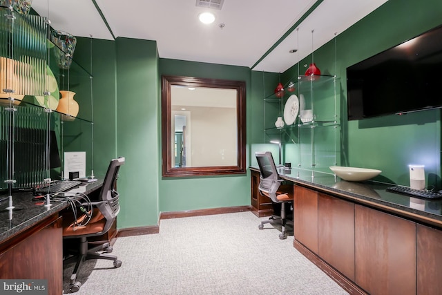 office space with visible vents, light colored carpet, baseboards, and built in desk