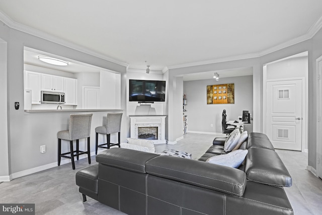 living area featuring a fireplace with raised hearth, baseboards, and ornamental molding