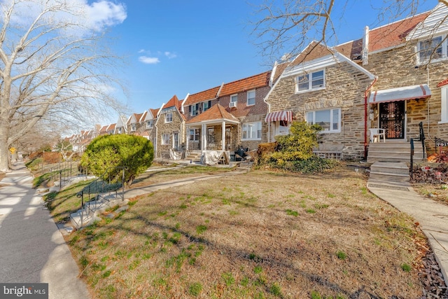 rear view of property featuring stone siding and a residential view