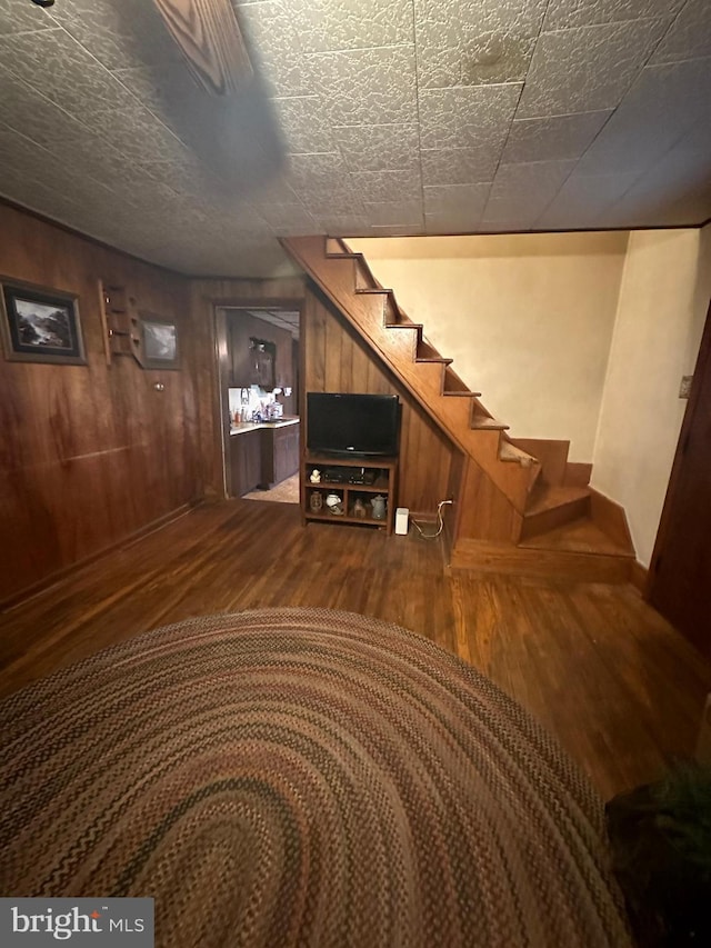 below grade area with wooden walls, stairs, and dark wood-type flooring