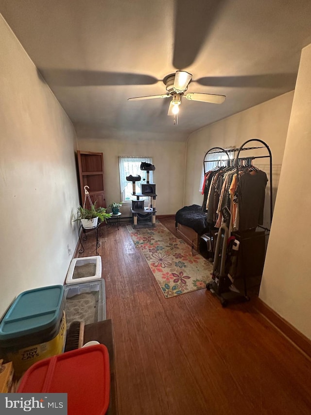 interior space with a ceiling fan, baseboards, and wood-type flooring