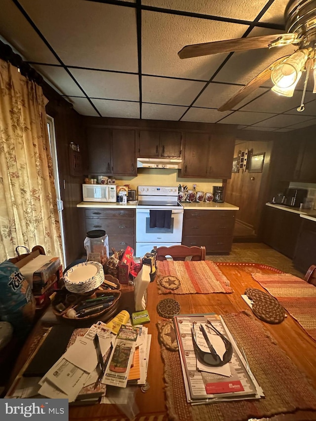 kitchen featuring under cabinet range hood, a paneled ceiling, white appliances, and light countertops