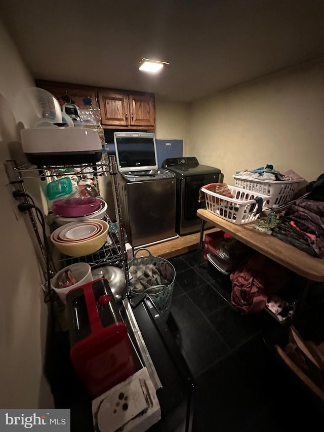 washroom with dark tile patterned floors, washing machine and dryer, and laundry area