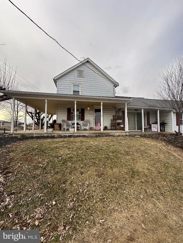 country-style home featuring a front yard, a carport, and covered porch