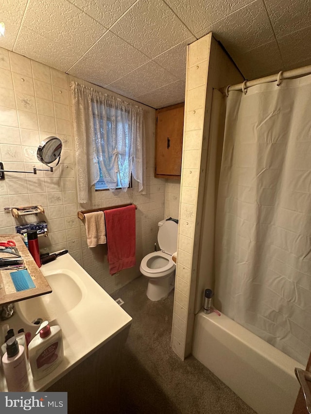 full bathroom with a drop ceiling, shower / bath combination with curtain, toilet, and tile walls