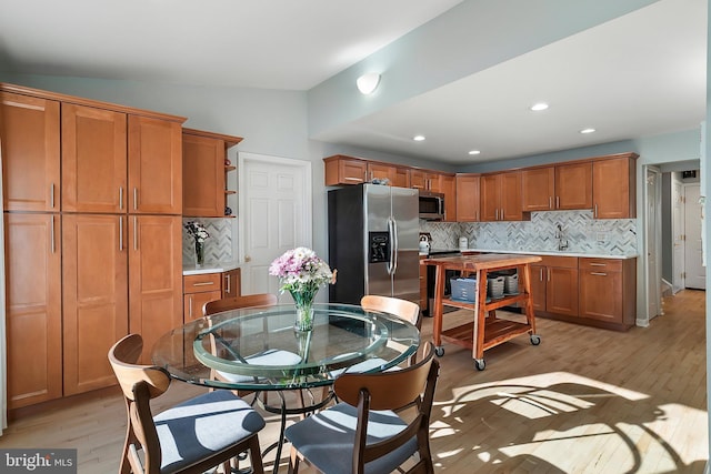 kitchen featuring brown cabinetry, light wood finished floors, open shelves, stainless steel appliances, and light countertops