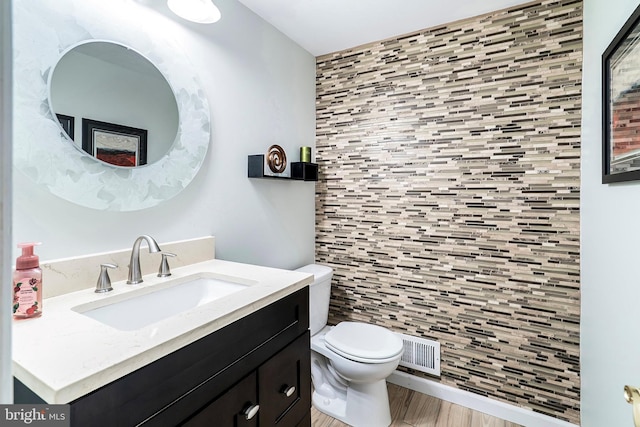 bathroom with visible vents, toilet, wood finished floors, and vanity