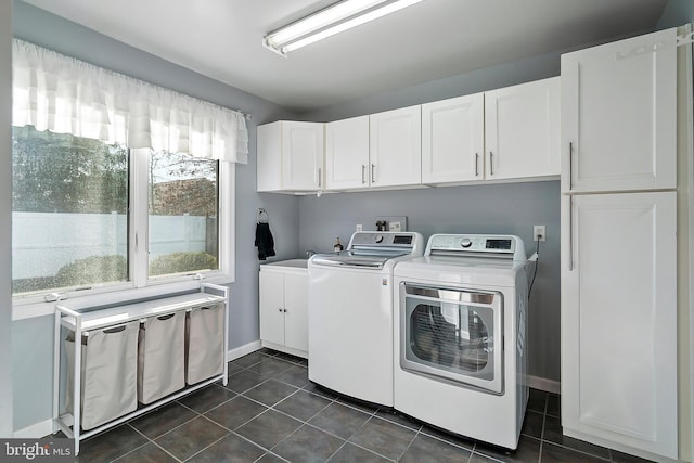 washroom with washer and clothes dryer, cabinet space, baseboards, and dark tile patterned floors