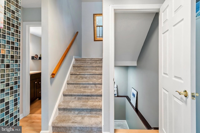 stairs with wood finished floors and baseboards