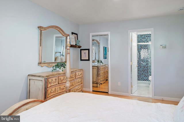 bedroom featuring ensuite bathroom, baseboards, and wood finished floors