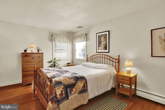 bedroom with visible vents, baseboards, and wood finished floors