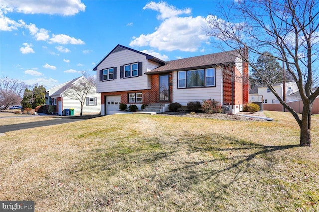 split level home with a front yard, fence, driveway, an attached garage, and brick siding