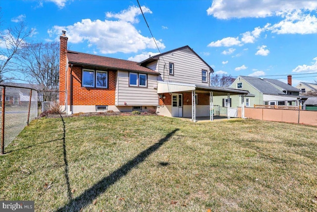 rear view of house featuring brick siding, a fenced backyard, a lawn, and a chimney