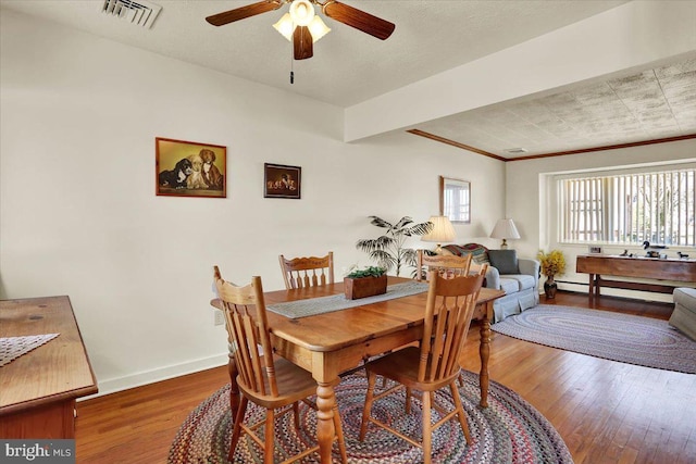 dining space featuring baseboards, visible vents, wood-type flooring, and a baseboard radiator