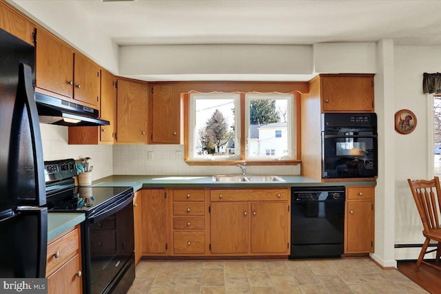 kitchen featuring black appliances, a sink, a baseboard heating unit, under cabinet range hood, and tasteful backsplash