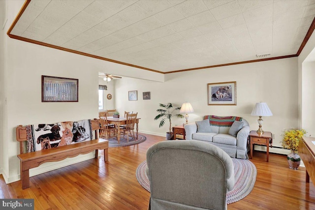 living area with visible vents, baseboards, a baseboard radiator, ornamental molding, and hardwood / wood-style flooring