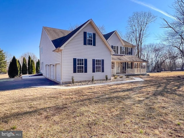 traditional home featuring covered porch, an attached garage, driveway, and a front yard