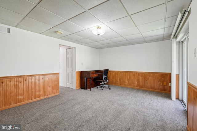 unfurnished office featuring a wainscoted wall, visible vents, wooden walls, and carpet floors