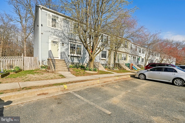 multi unit property with fence, uncovered parking, and a residential view