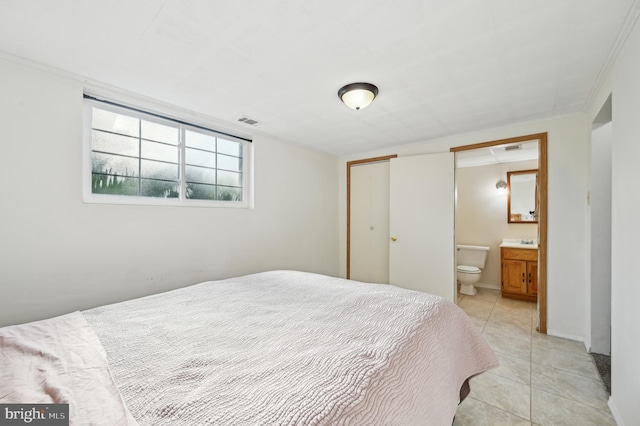 bedroom featuring connected bathroom, visible vents, and light tile patterned floors