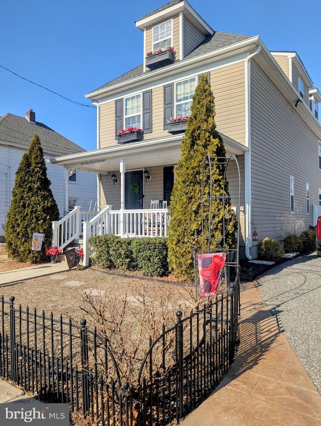 traditional style home with a fenced front yard and covered porch