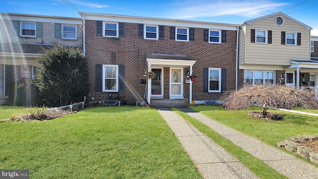 view of front facade with brick siding and a front yard