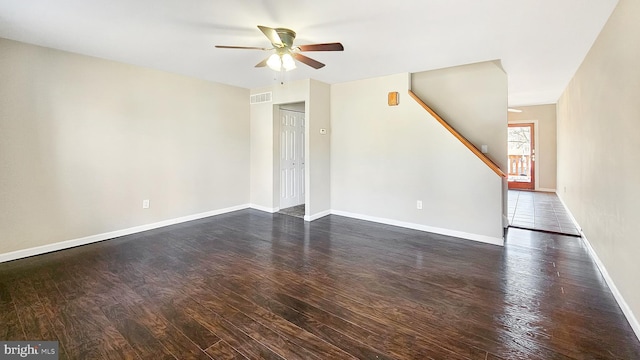 unfurnished living room with visible vents, dark wood-type flooring, a ceiling fan, baseboards, and stairs