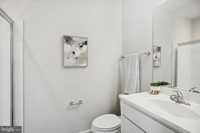 full bathroom with vanity, toilet, baseboards, and a tile shower