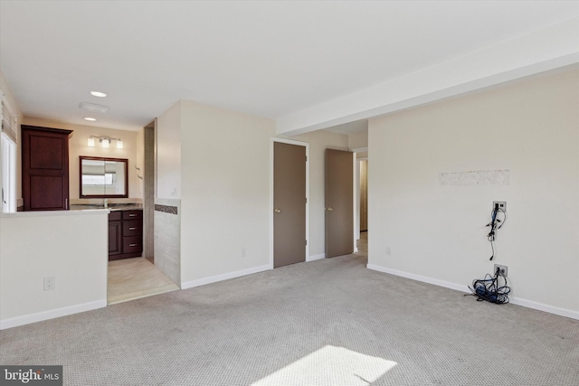 unfurnished living room with baseboards and light colored carpet