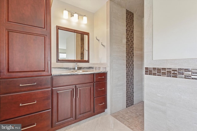 full bath featuring tile patterned floors, tile walls, vanity, and a tile shower