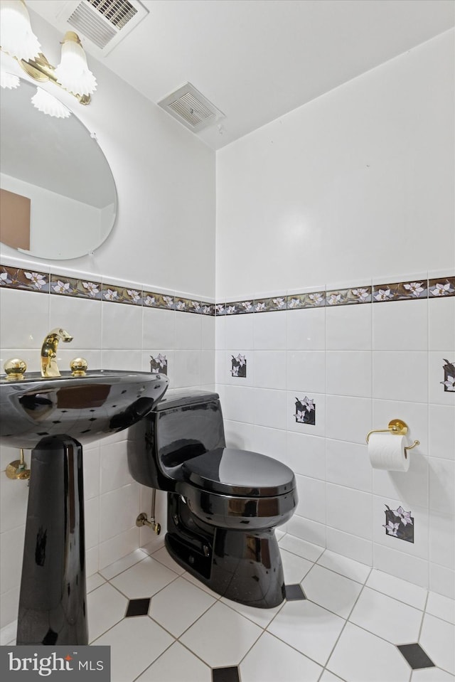 bathroom with tile patterned floors, toilet, tile walls, and a sink