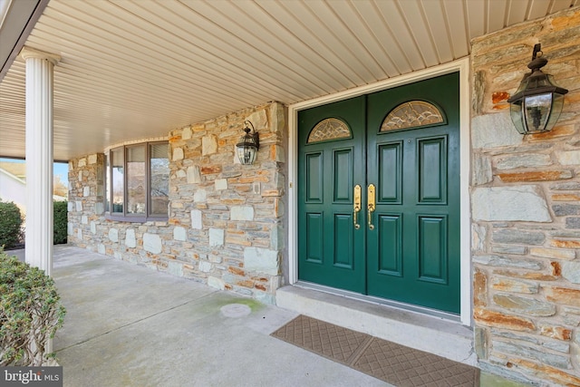 entrance to property with stone siding and a porch