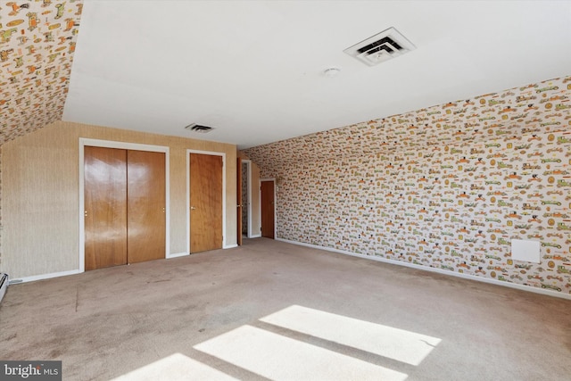 unfurnished bedroom with visible vents, multiple closets, and carpet floors