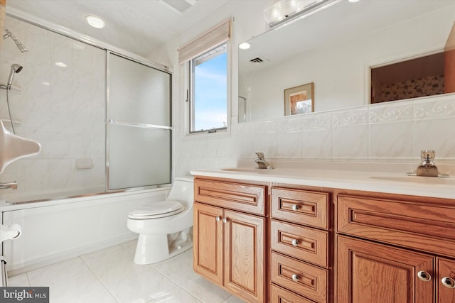 full bath featuring visible vents, toilet, a sink, tile walls, and double vanity