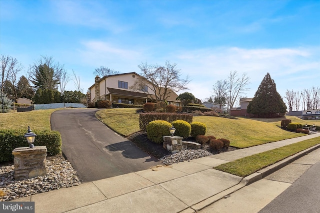 view of front facade featuring a front lawn, driveway, and fence