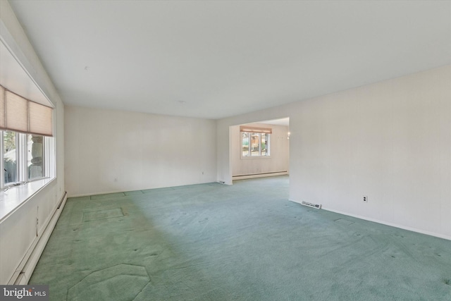 carpeted spare room featuring plenty of natural light, visible vents, and a baseboard radiator