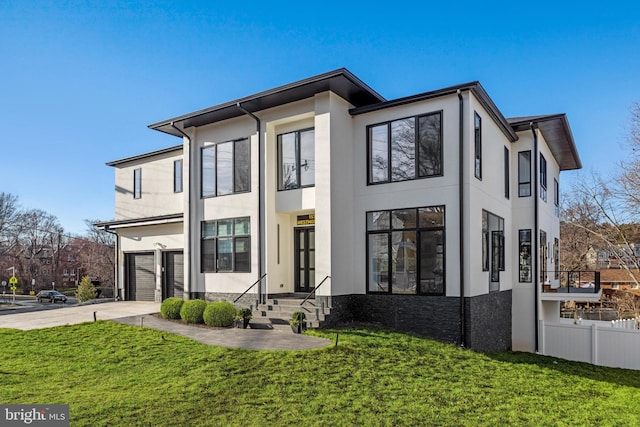 view of front of property with fence, concrete driveway, a front yard, stucco siding, and a garage