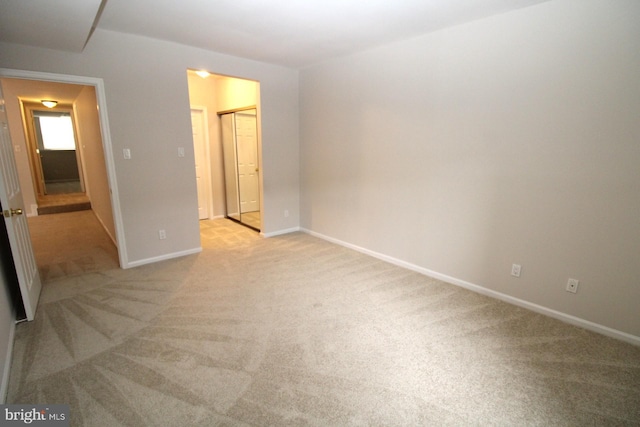 unfurnished bedroom with baseboards, light carpet, and a closet