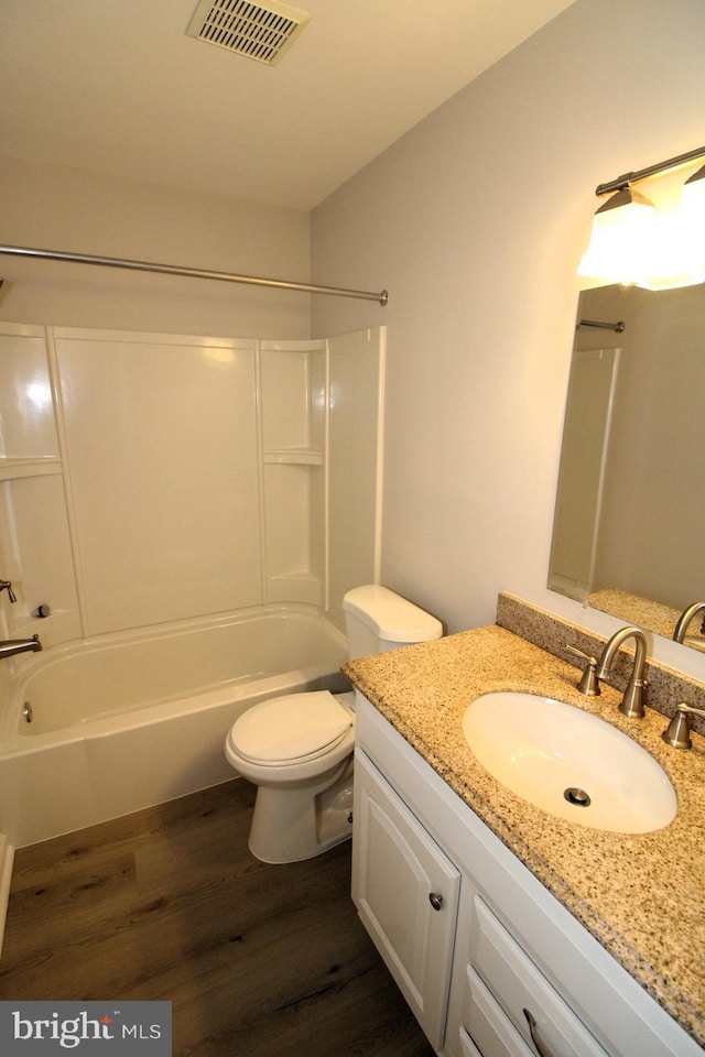 bathroom with visible vents, wood finished floors, toilet, and shower / washtub combination