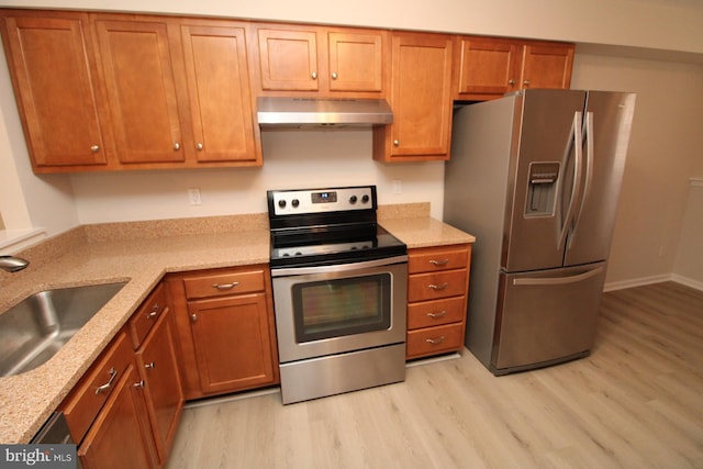 kitchen featuring a sink, stainless steel appliances, brown cabinets, and wall chimney exhaust hood