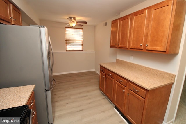 kitchen featuring brown cabinets, a ceiling fan, black electric range, freestanding refrigerator, and light wood finished floors