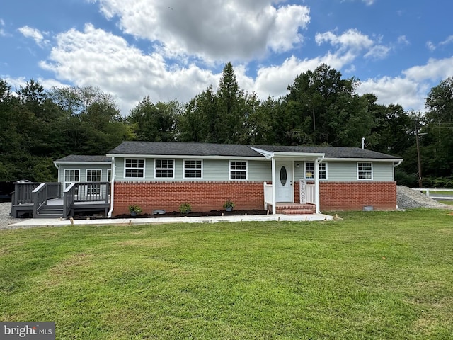 ranch-style home with brick siding, a wooden deck, and a front yard