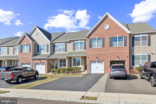 multi unit property featuring driveway, brick siding, an attached garage, and a shingled roof