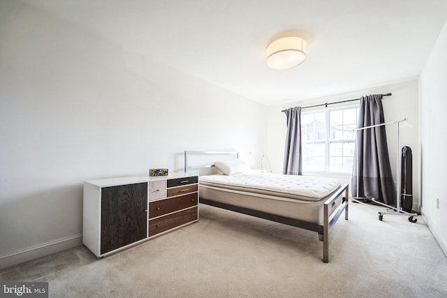 bedroom with light colored carpet and baseboards